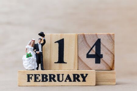 Miniature people couple with wooden block 14 FEB on wooden background, happy valentines day conceptの写真素材