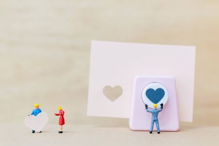 Miniature people : Couple with  paper heart on wooden  background , Valentine's Day conceptの写真素材