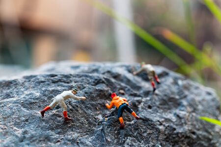 Miniature people: Hikers climbing up on the rock . Sport and leisure conceptの写真素材