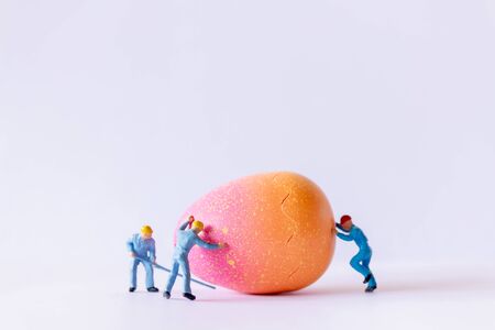 Miniature people Worker team working at Easter-eggs for Easter day on white background