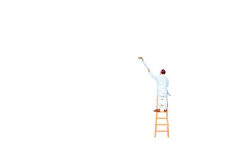 Miniature people with ladder holding brush in front of a white wall backgroundの写真素材
