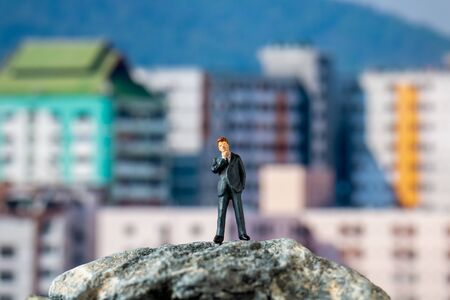 Miniature people , Businessman standing on The rock with building backgroundの写真素材