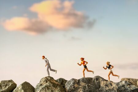 Miniature people : Running on rock cliff with nature background , Health And lifestyle concepts