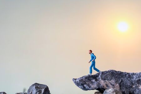 Miniature people : Running on rock cliff with nature background , Health And lifestyle conceptsの写真素材