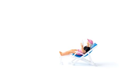 Miniature people sunbathing on deck chairs on white background , Summer time conceptの写真素材
