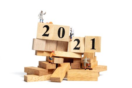 Miniature people: climb up on wooden cube with number 2021, Happy new year conceptの写真素材