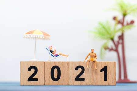 Miniature people wearing swimsuit sitting on the lounge chair at wooden block 2021の写真素材