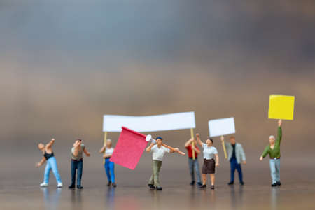 Miniature people , Crowd of protesters people raised hands and shouting on wooden background.の写真素材