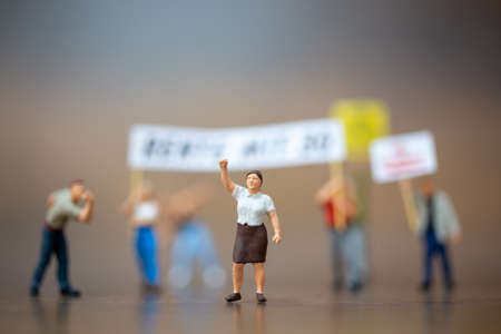 Miniature people , Crowd of protesters people raised hands and shouting on wooden background.の写真素材