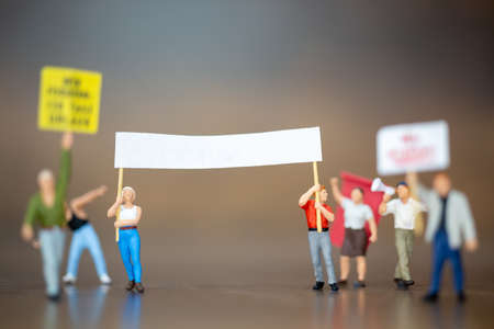 Miniature people , Crowd of protesters people raised hands and shouting on wooden background.の写真素材