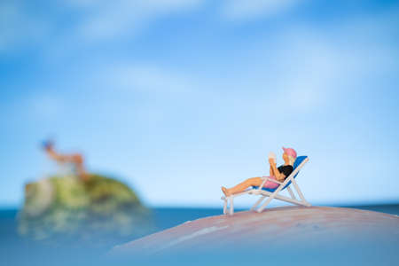 Miniature people sunbathing on a seashell with blue sky background  , summer vacation concept