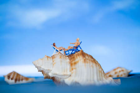 Miniature people sunbathing on a seashell with blue sky background  , summer vacation conceptの写真素材