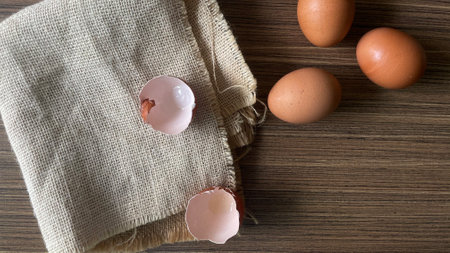 brown eggs on a wooden table with a burlap cloth, top viewの写真素材
