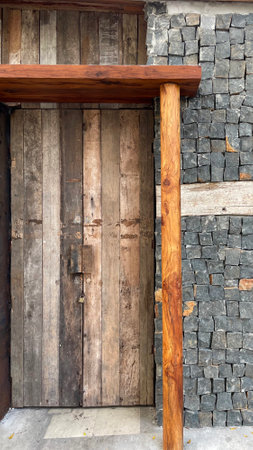 Wooden door of an old wooden house with a stone wall.の写真素材