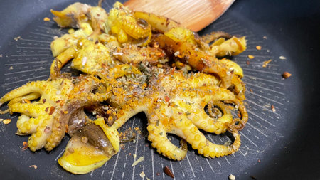 Fried octopus in a frying pan with spices and olive oil