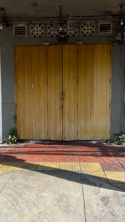 Old yellow wooden door and pavement in the old town of Bangkok, Thailandの写真素材