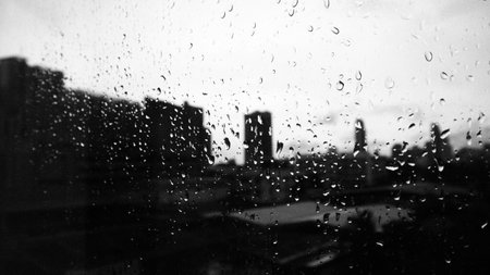 Rain drops on window glass with cityscape background. Black and whiteの写真素材
