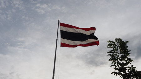 Thailand flag waving in the wind against the blue sky and white clouds
