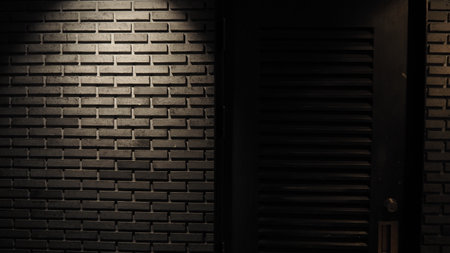 Black brick wall background with light from the window. Abstract background.の写真素材