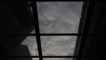 A low angle shot of a window with a cloudy sky in the background