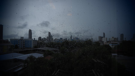 Rain drops on the window with cityscape in the background. Selective focus.