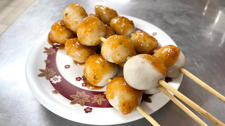 Meatballs with sweet and sour sauce in white plate on stainless steel table