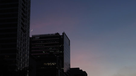 Silhouette of skyscrapers and the moon in the eveningの写真素材