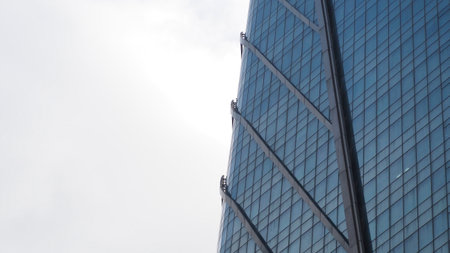 Bottom view of modern skyscrapers in business district against blue skyの写真素材