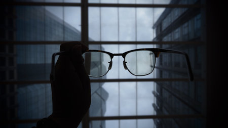 Glasses in hand on the background of the window of a skyscraperの写真素材