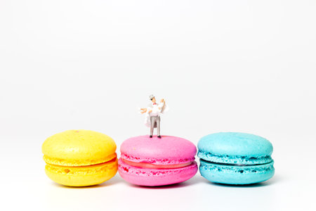 Miniature people , Bride and groom on colourful french macaroon , Valentines day concept