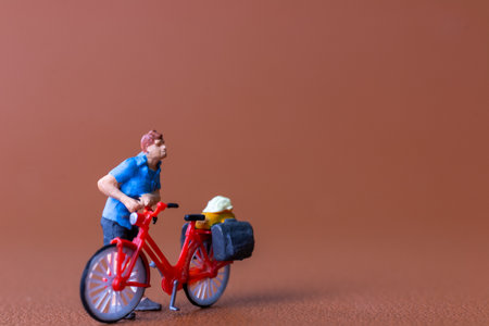 Miniature figure of a cyclist wearing a blue shirt, standing next to a red bicycle loaded with travel bags. Perfect for themes of travel, adventure, or hobbies.の写真素材