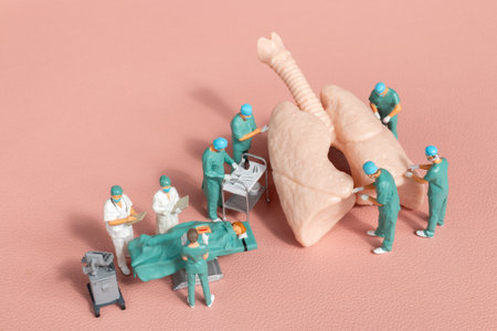 Miniature figures, medical team performing surgery on a detailed anatomical lung model on a pastel pink backgroundの写真素材