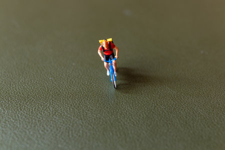 Close-up shot of a figurine of a cyclist riding a blue bicycle with a backpack, Perfect for themes...