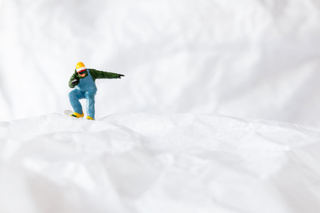 Miniature people  snowboarder dressed in vibrant winter gear, carving through a snowy slope. Ideal for winter sports, adventureの写真素材