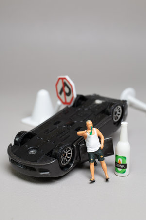 Miniature people, A Drunk driver holding a liquor bottle as he steps out of a car. concepts of reckless behavior, urban lifeの写真素材