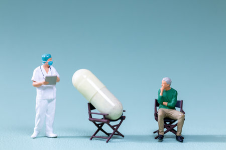 Miniature figurine doctor, a patient, and an oversized pill seated on a chairs, symbolizing medical discussions, drug efficacy, or healthcare decisions.の写真素材