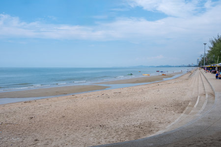 Peaceful morning view of Cha-am Beach in Thailand, featuring a clean sandy shoreline, gentle waves, and a bright blue skyの写真素材