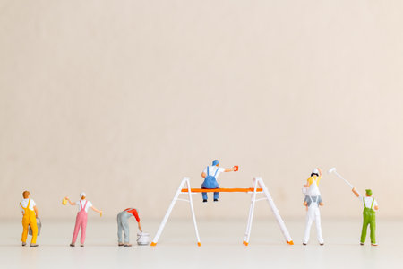 Figurines of painters working together on a blank beige wallの写真素材