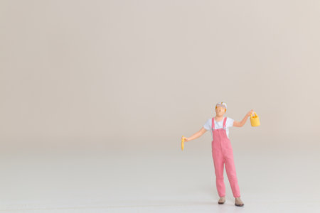 Miniature Painter Holding Paint Bucket and Brush against a soft neutral backgroundの写真素材