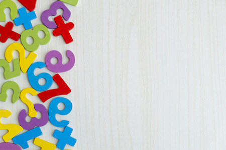 Top view of colorful wooden numbers and letters scattered on wooden table