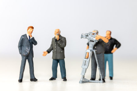 Miniature figure of a male journalist interviewing a businessman, with a cameraman recording. This scene represents the communication process in journalism and businessの写真素材