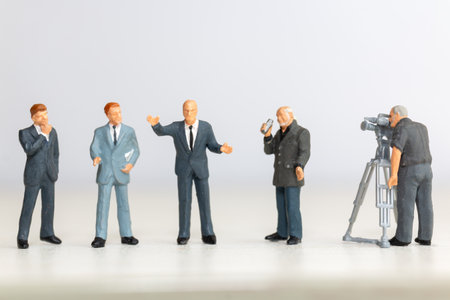 Miniature figure of a male journalist interviewing a businessman, with a cameraman recording. This scene represents the communication process in journalism and businessの写真素材