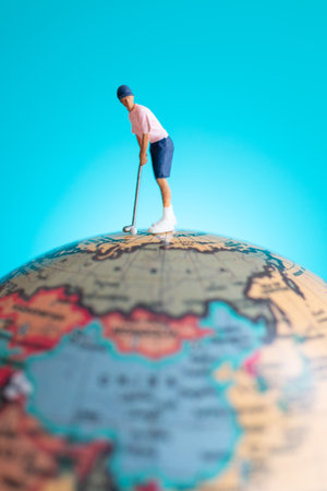A miniature figure of a golfer playing on top of a globe, symbolizing global sport, travel, and imagination.の写真素材