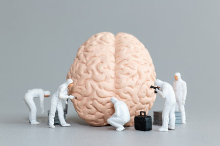 Miniature figures in hazmat suits inspect and analyze a giant brain model