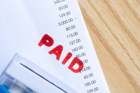 Close up of red paid stamp on bill receipt document with numbers, symbolizing payment, finance, and...