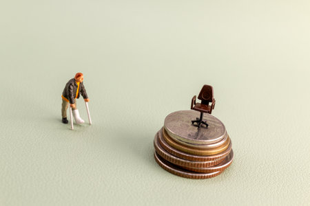 Conceptual photo of a miniature man with crutches standing on coins, looking at an office chair placed on higher stacks of coins, symbolizing challenges, inequality, and career obstaclesの写真素材