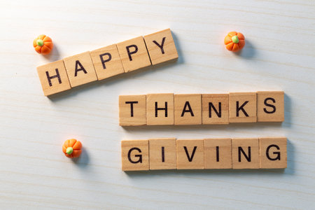 Top view of wooden letter Happy Thanksgiving with mini pumpkins on light wood background, festive minimal holiday concept.の写真素材