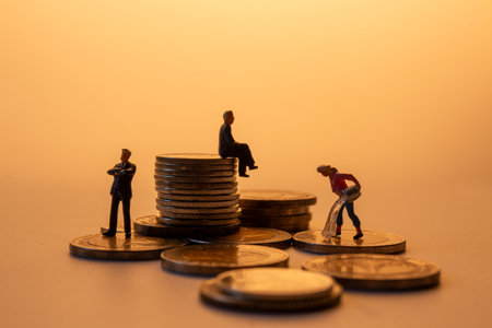 Conceptual image of miniature figures on stacked coins representing money laundering, financial...