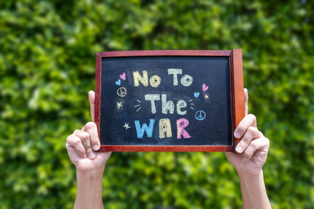 Hands holding a small chalkboard with the message â€œNo To The Warâ€ written in colorful...