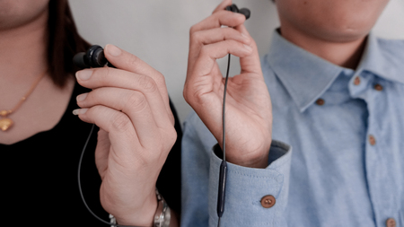 Couples are wearing the same headphones to listen to music from mobile phones.の写真素材